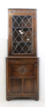 A reproduction carved oak part-glazed corner cabinet - the lunette carved frieze over a leaded glass