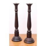 A pair of stained wooden turned pricket candlesticks - 60.5cm. high.