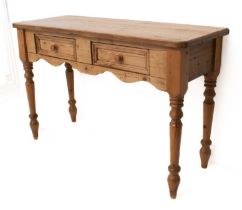 A 19th century style waxed pine two-drawer side table - the boarded top with rounded front angles,