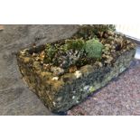 A carved limestone garden trough - well weathered, with rock feature and planted with alpines. (