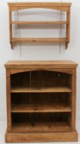 A waxed-pine open bookcase of small proportions - the moulded top over an arched apron and three