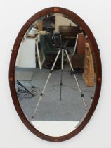 An Edwardian oval inlaid mahogany mirror - the bevelled plate within a boxwood strung frame with