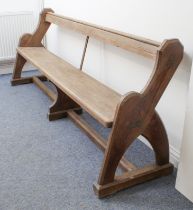 A Victorian pitch pine church pew - the open back headed by a moulded rail with bookshelf to back,