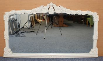 A carved off-white painted wooden overmantle mirror in the 19th century style - the shaped, bevelled