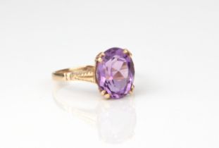A 9ct yellow gold and amethyst ring - stamped '9CT', the 11 x 9mm. oval cut amethyst over bright cut