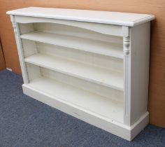 An off-white painted pine open bookcase - the moulded top above an arched frieze and three