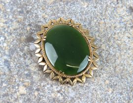 A 9ct yellow gold and jade brooch - stamped '9CT', the oval 31 x 23mm. stone within a pierced,