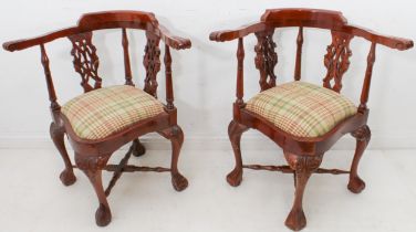 A pair of reproduction George II style carved mahogany corner chairs - the scroll carved arms over a