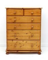 A pine six-drawer chest - with bowfronted top with eared front angles and turned handles, with two