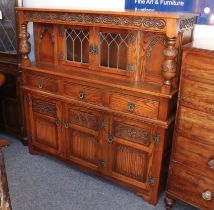 A reproduction oak court cupboard by Old Charm - the top with a foliate scroll carved frieze over