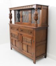 A reproduction carved oak court cupboard - the back with three leaded glass panels with central