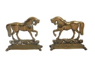 A mirrored pair of 19th century brass door stops in the form of horses - standing on foliate