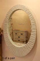 A pair of oval modern mirrors - the asymmetric moulded, oval frames with an angular textured