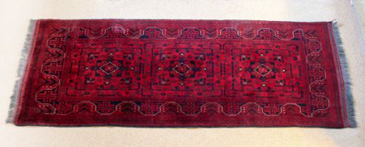 An Afghan Kundoz rug - with three square medallions and all over floral decoration on a red field,