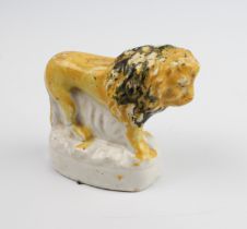 A small 19th century century Staffordshire figure of a lion - painted yellow and black over a