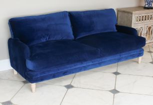 A Loaf Squisheroo three seater settee - upholstered in Royal blue velvet, raised on turned limed oak