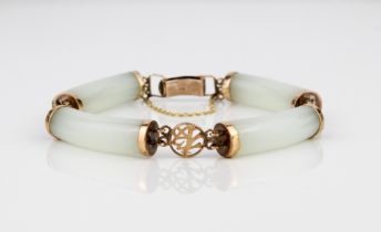 A Chinese 9ct gold and celadon jade bracelet - with four curved, cylindrical jade bars joined by