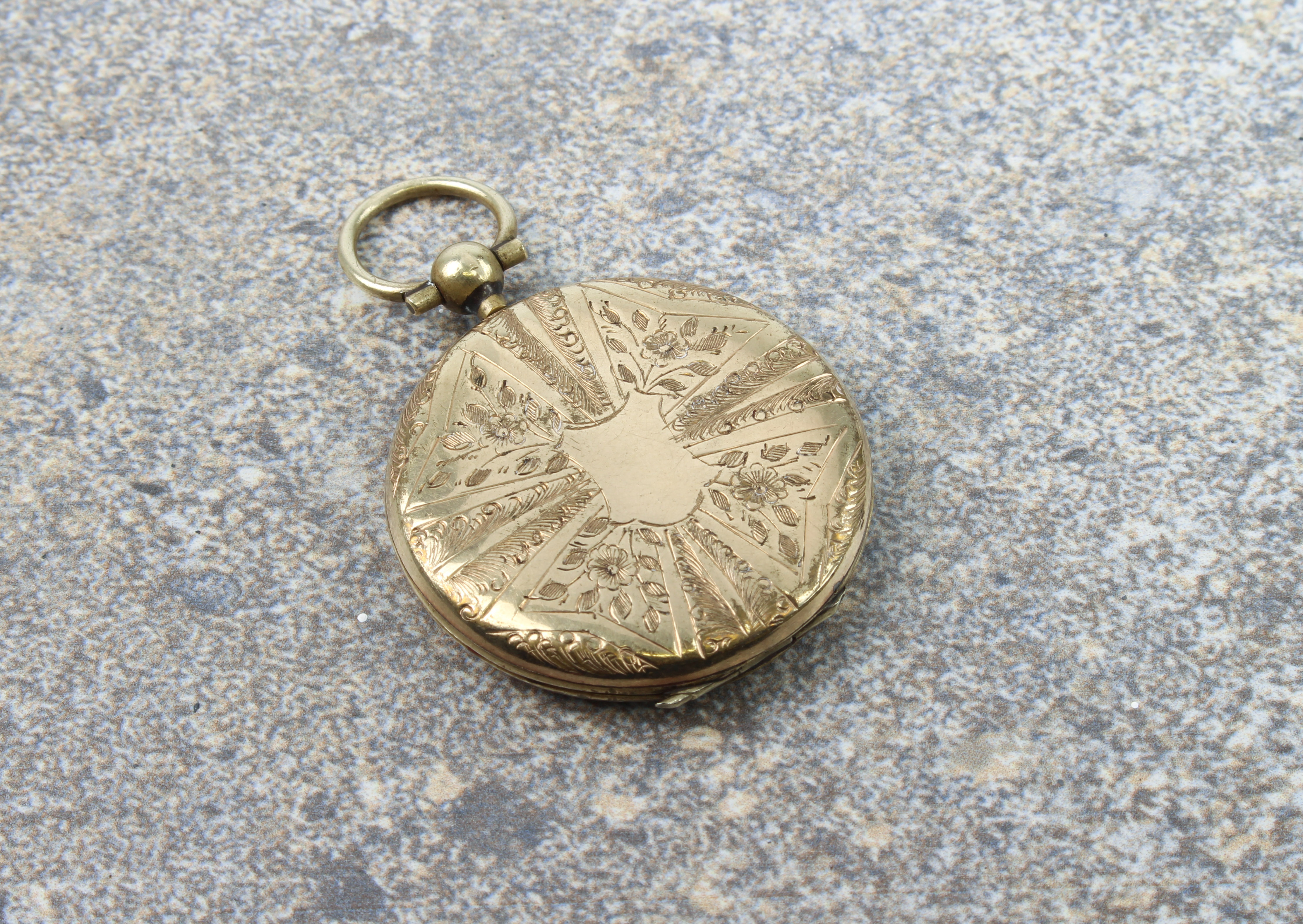 A late Victorian rolled gold locket - circular, chased with flowers and foliage in a radial pattern,