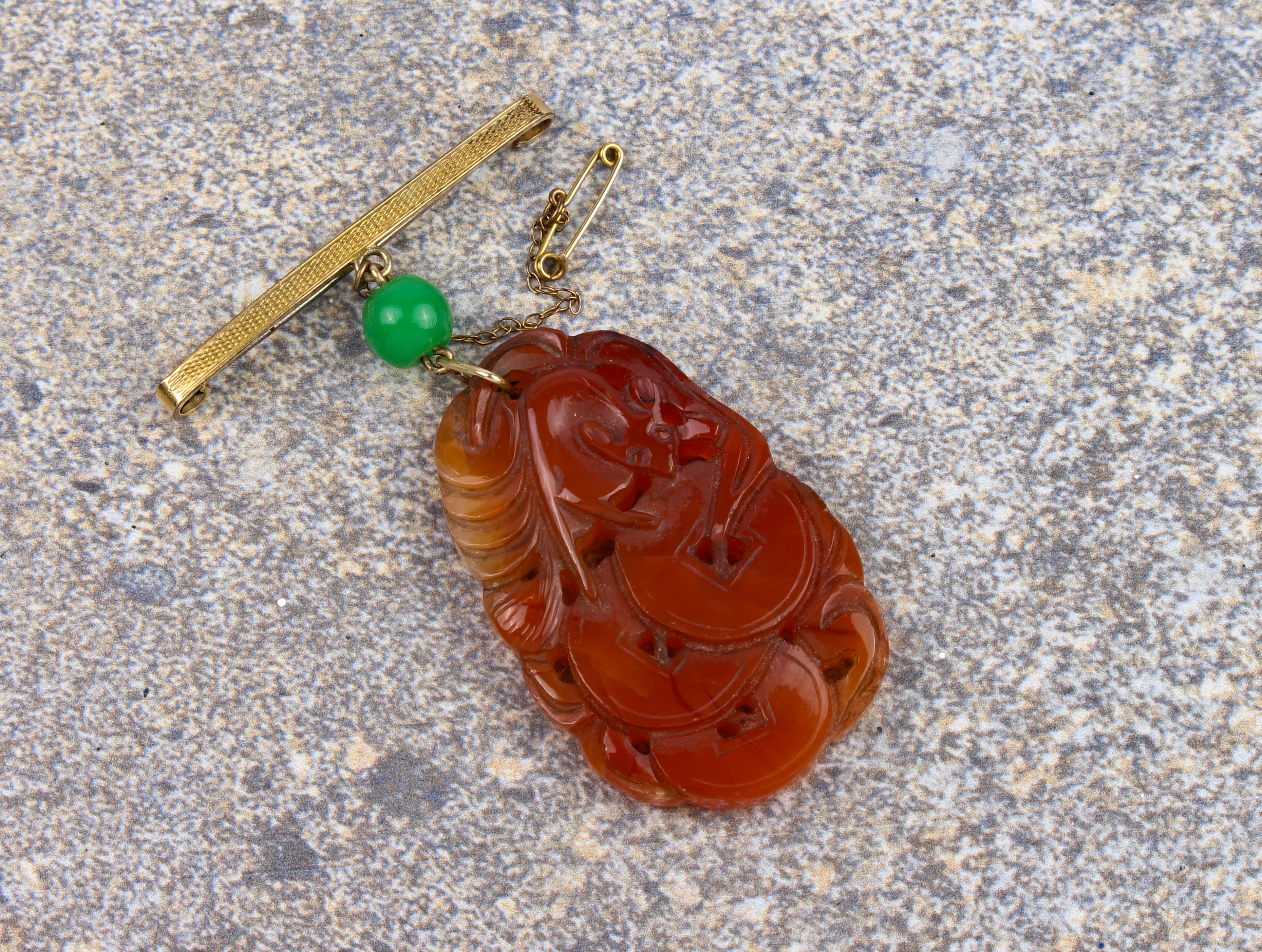 A mid-century Chinese carved jade plaque on bar brooch - the ovoid, russet jade plaque pierced and