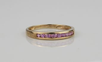 A 9ct gold and pink sapphire channel-set ring - with nine round cut sapphires, hallmarked QVC