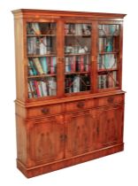 A reproduction Georgian-style yew veneered library bookcase - the dentil carved cornice over three