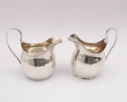 A pair of Edwardian silver helmet cream jugs in the George III style - C. S. Harris & Sons Ltd.,