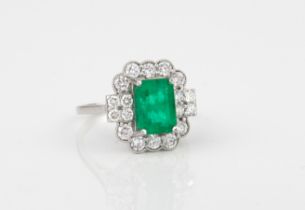 A platinum, emerald and diamond cluster ring - the 8.5 x 6mm emerald within a border of ten