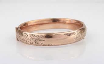 A silver and rolled gold hollow, hinged bangle, c.1900 - chased with foliate scrolls.