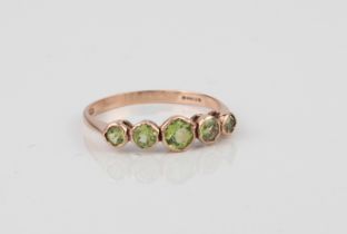 An antique 9ct rose gold and peridot five-stone ring - hallmarked London 1909, the five graduated