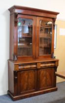 A Victorian mahogany glazed cupboard bookcase - the moulded cavetto cornice on foliate carved
