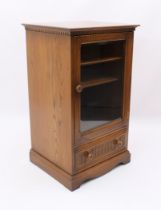 An Ercol elm hi-fi cabinet - with dentil frieze over a glazed door enclosing two shelves, above a