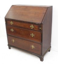 A George III oak bureau - the simple interior with three drawers and an open shelf above, over three