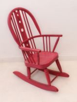 A pink painted Windsor-style child’s rocking chair: mid-20th century, the hoop back with pierced