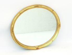 An oval gilt antique-style wall mirror - 65.5 x 58.5 cm.