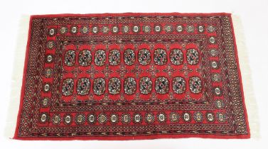 A Pakistan Bokhara rug - retailed by G. H. Frith Ltd., with two rows of nine gols on a red ground,