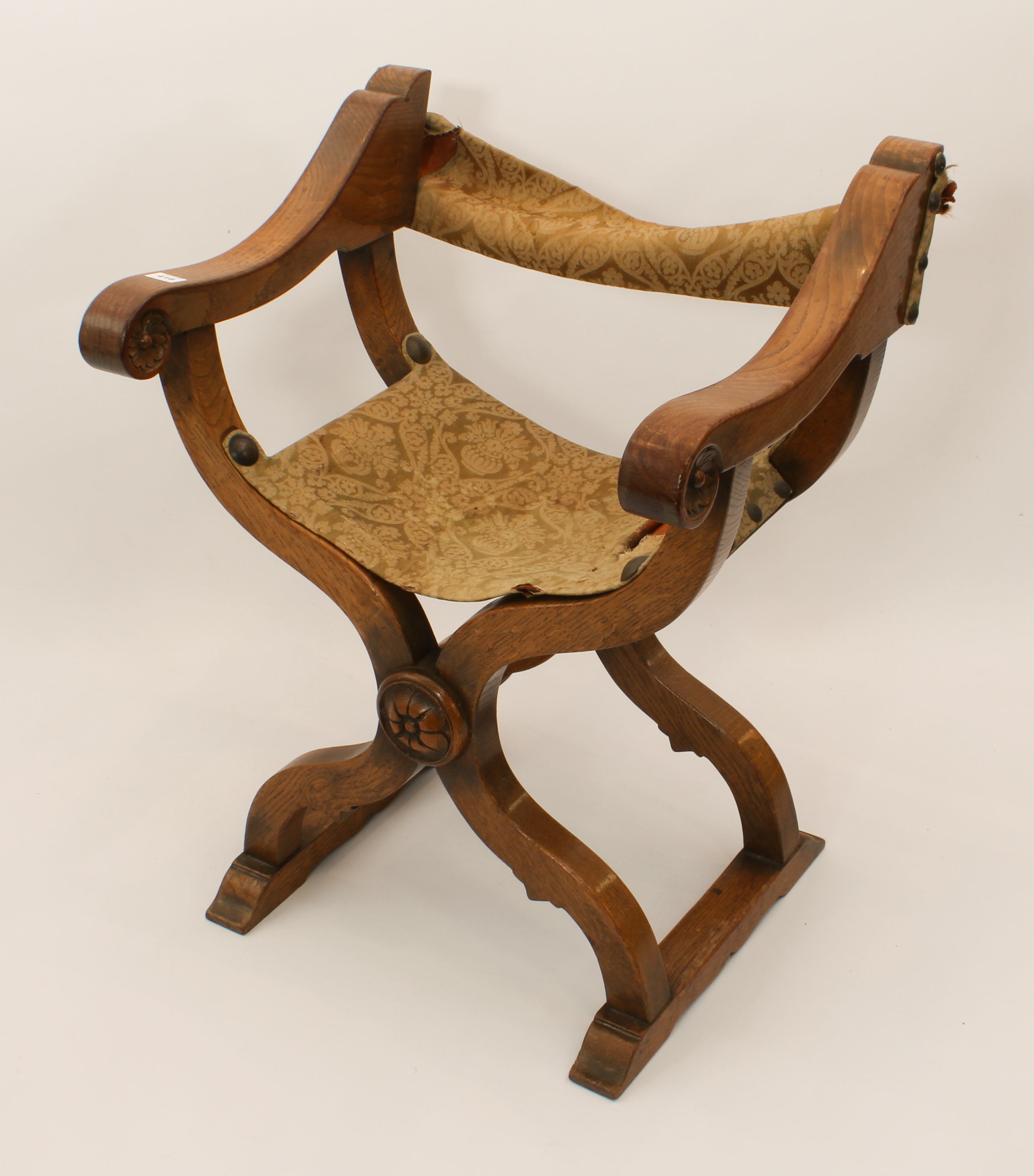 A late 19th century mid-oak and leather x-framed chair - the leather back and slung seat covered