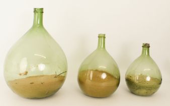 Three graduated blown green glass demijohns - probably late 19th / early 20th century, the larger 45