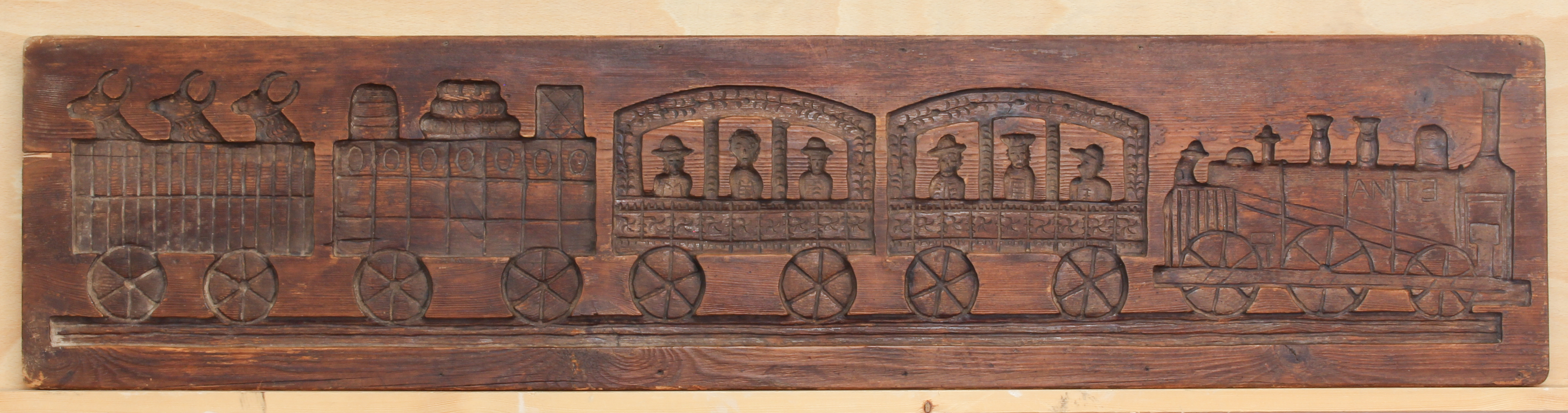 A vintage stained pine panel or mould carved in counter-relief with a steam train - 'Etna', with two