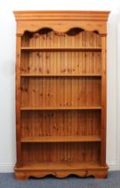 A modern pine open bookcase - the ogee moulded cornice over a serpentine frieze, above four