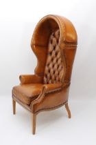 A Georgian-style tan leather and walnut porter's chair - the shaped, hooded back with brass