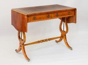 A reproduction Regency style yew veneered sofa table - the cross-banded top with serpentine