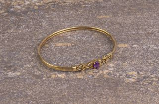 A 9ct yellow gold and amethyst bangle - unmarked, tests as 9ct gold, the single, oval amethyst in an