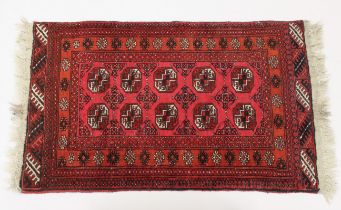 A small Bokhara style rug - with two rows of five octagonal medallions on a madder ground, within