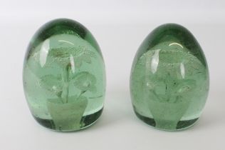 Two Victorian green glass dump paperweights - both with flower inclusions, the larger 11 cm high.