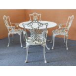 A white-painted cast metal circular garden table and four chairs - the table with pierced leafy