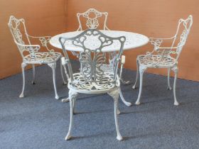 A white-painted cast metal circular garden table and four chairs - the table with pierced leafy