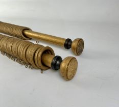 A pair of gilt painted wooden curtain poles - one with turned terminals with bronzed metal mounts,