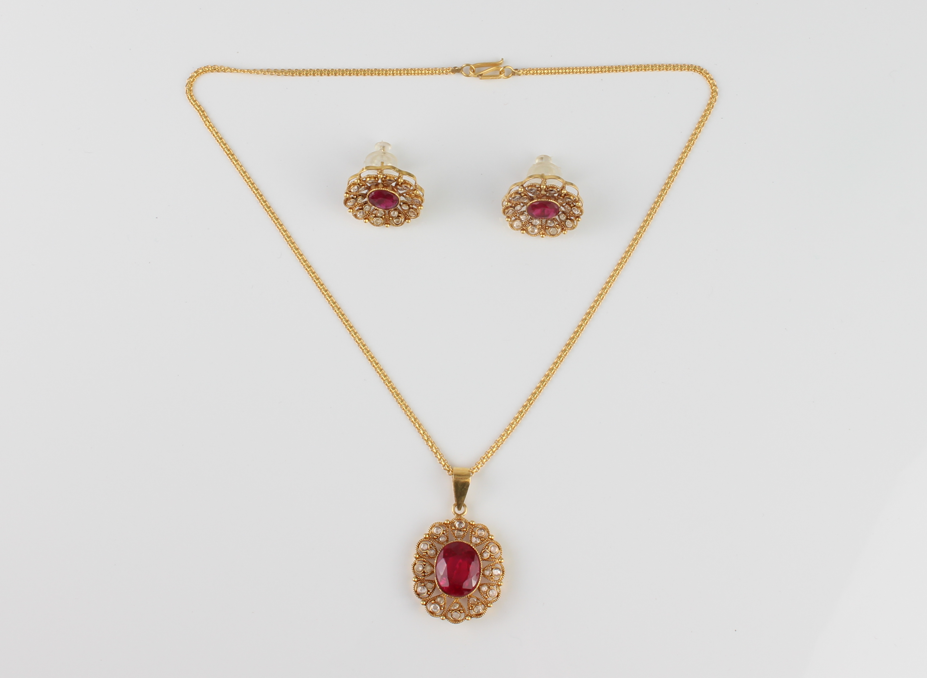 A 22ct gold, red stone and diamond cluster pendant necklace and earrings en suite - unmarked,