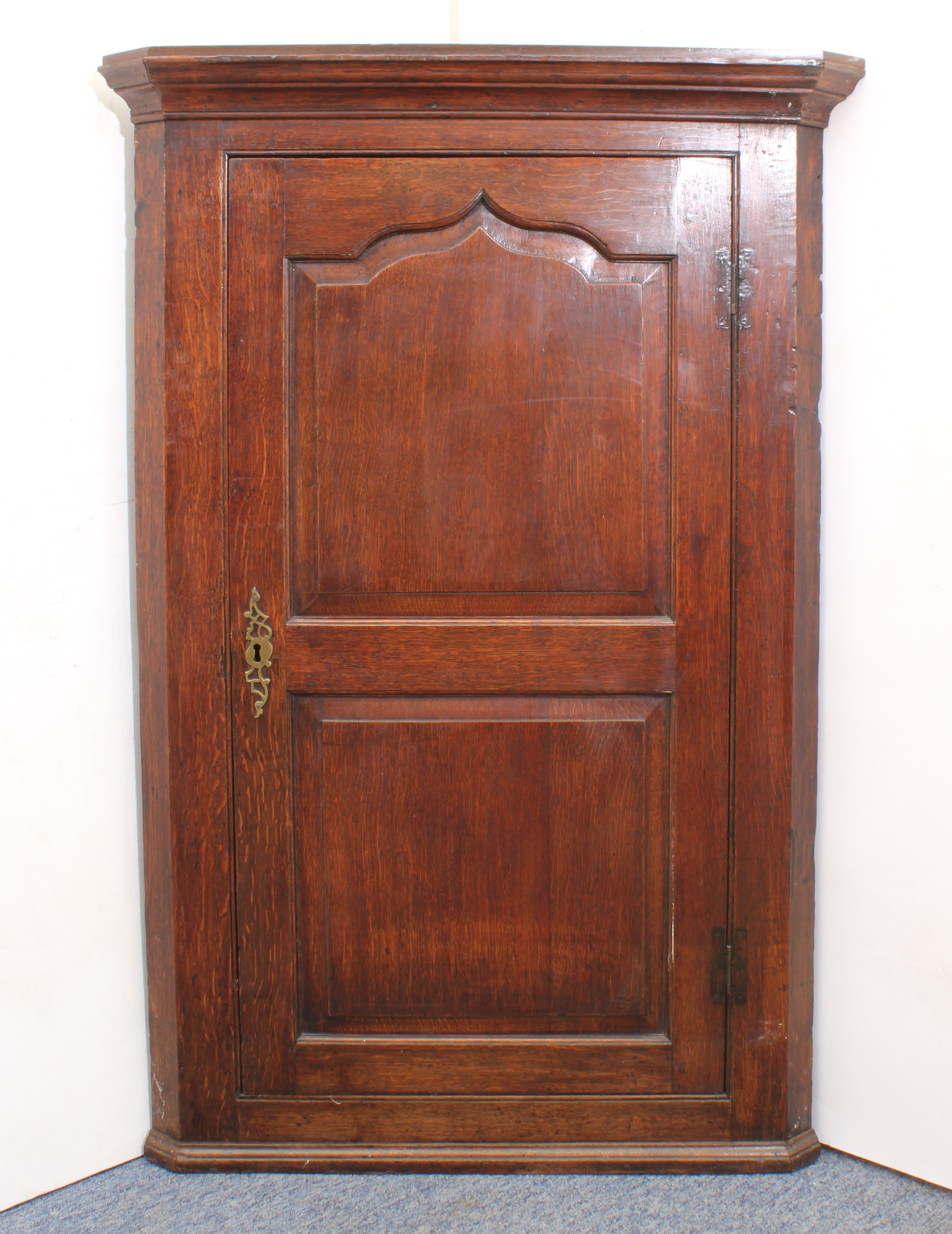 A large George III oak wall-hanging corner cupboard - the ogee moulded cornice over a two chamfer-