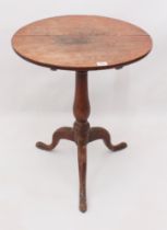 A George III oak tilt-top tripod table - the circular top on a turned baluster column to three swept